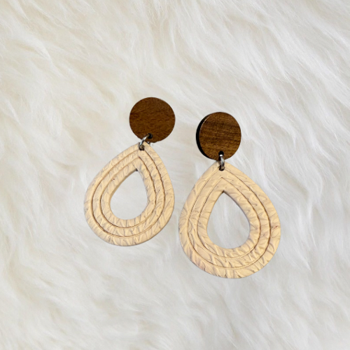 Handmade dangle earrings with a hollow teardrop shape and a textured cream color that resembles a windowpane. They are secured on a wooden circle, with stainless steel post back 